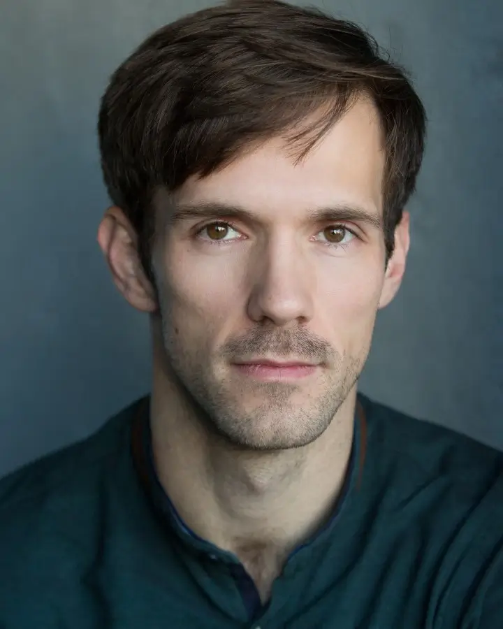 Headshot of Stephen Spencer Voice Actor. He's looking directly into the camera, with a textured grey/blue background.